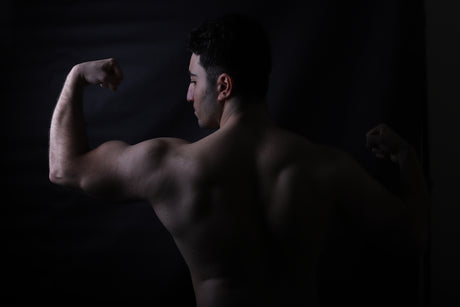 A bodybuilder flexes his biceps for the camera.