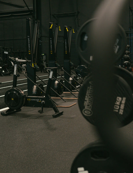 Rowing machines and weight plates in a gym.