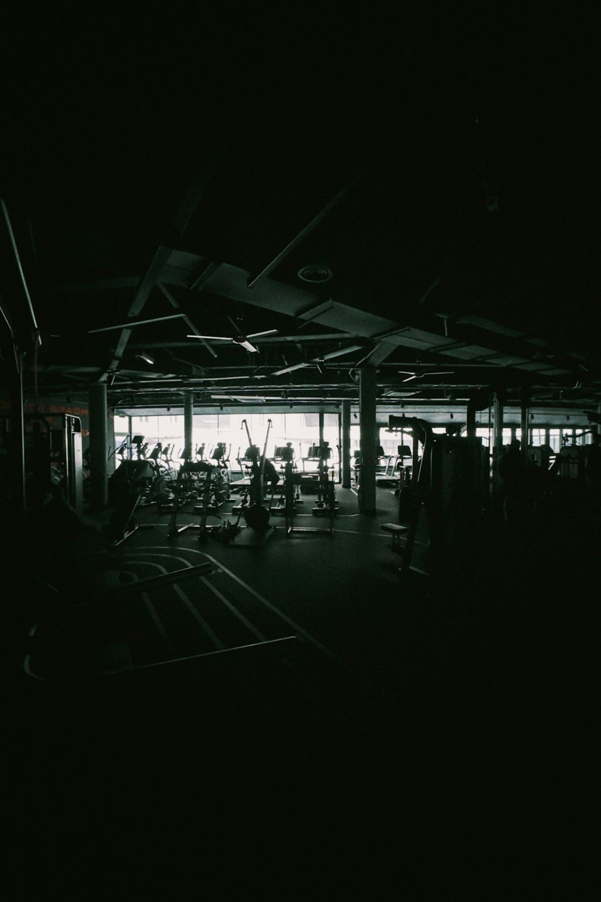 Dark gym interior with exercise equipment visible